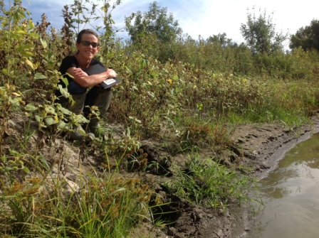 Woman sitting on river bank facing camera